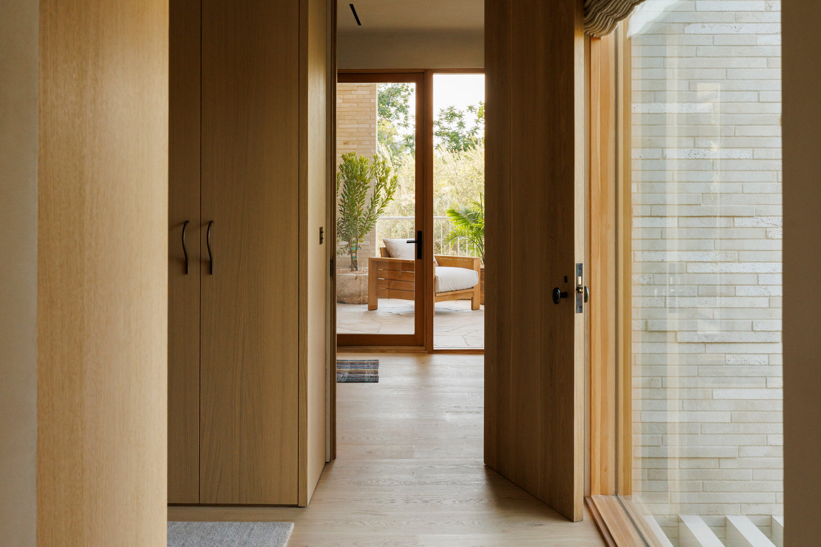 MADERA oak flooring and door frames create visual flow through this hallway, connecting interior spaces to outdoor living.