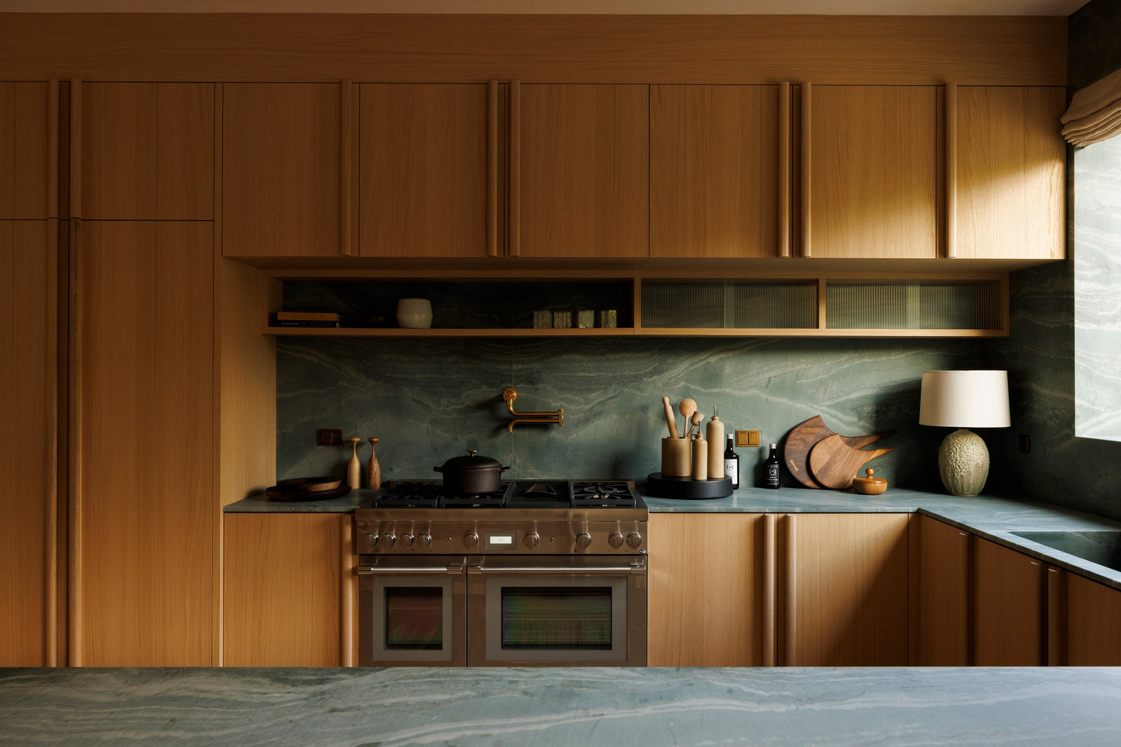 Full-height oak cabinetry with integrated display shelving showcases MADERA's commitment to functional elegance in the kitchen.