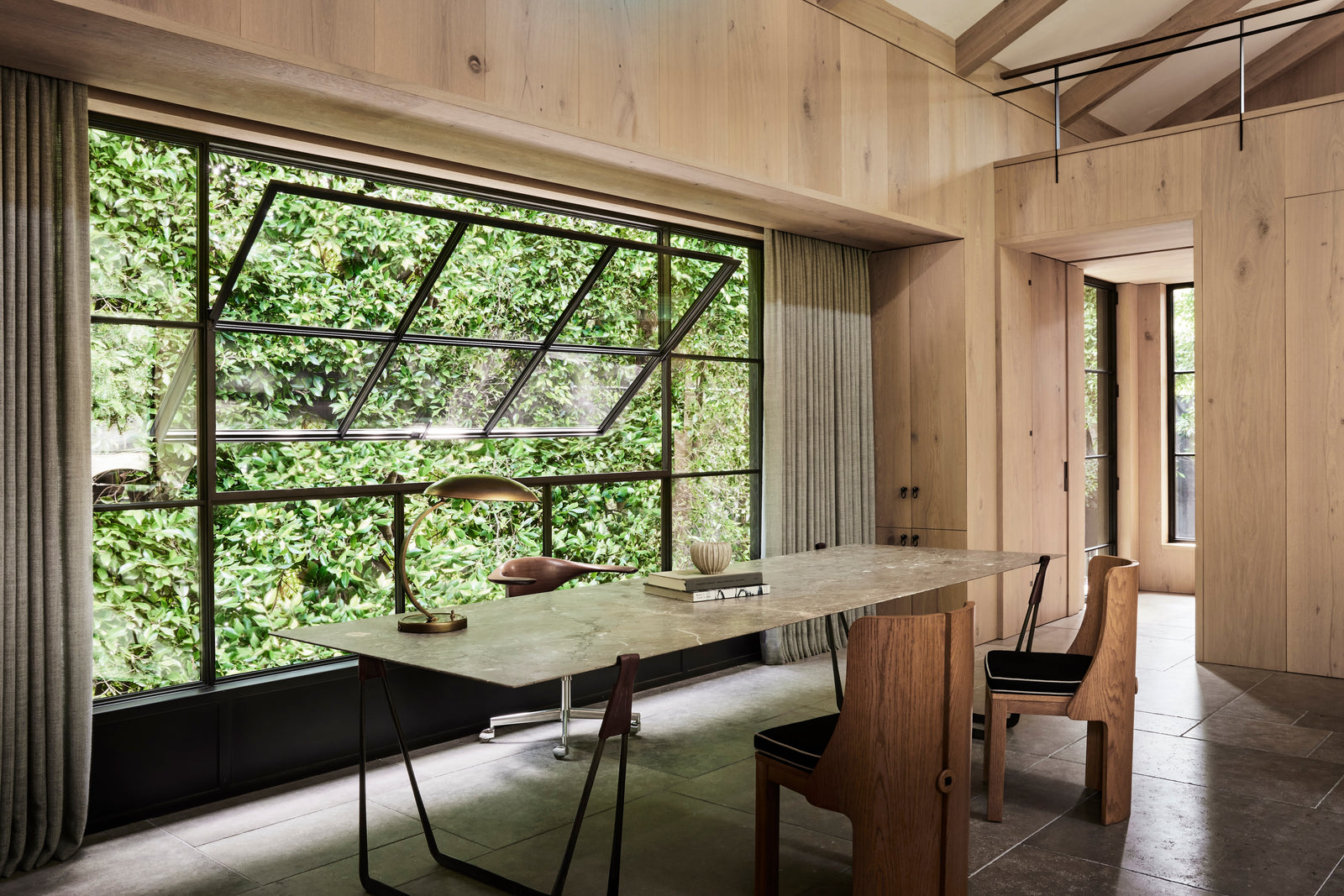 Material continuity in practice with heart oak cladding wrapping walls, ceilings, and millwork establishing spatial rhythm through seamless grain alignment.