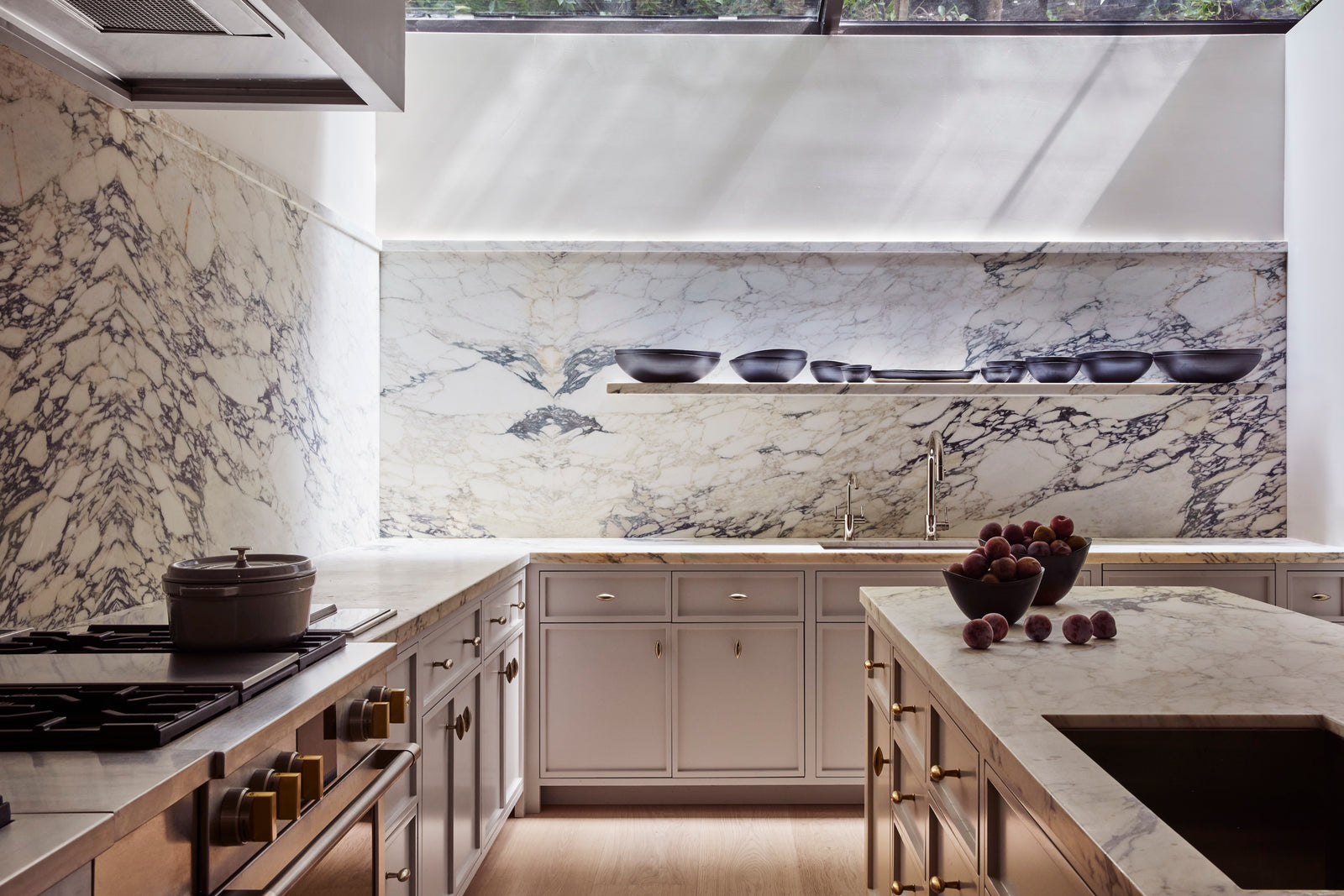 In the chef's kitchen, heart oak millwork forms a warm counterpoint to dramatic marble surfaces, grounding the space in natural texture while maintaining architectural clarity.