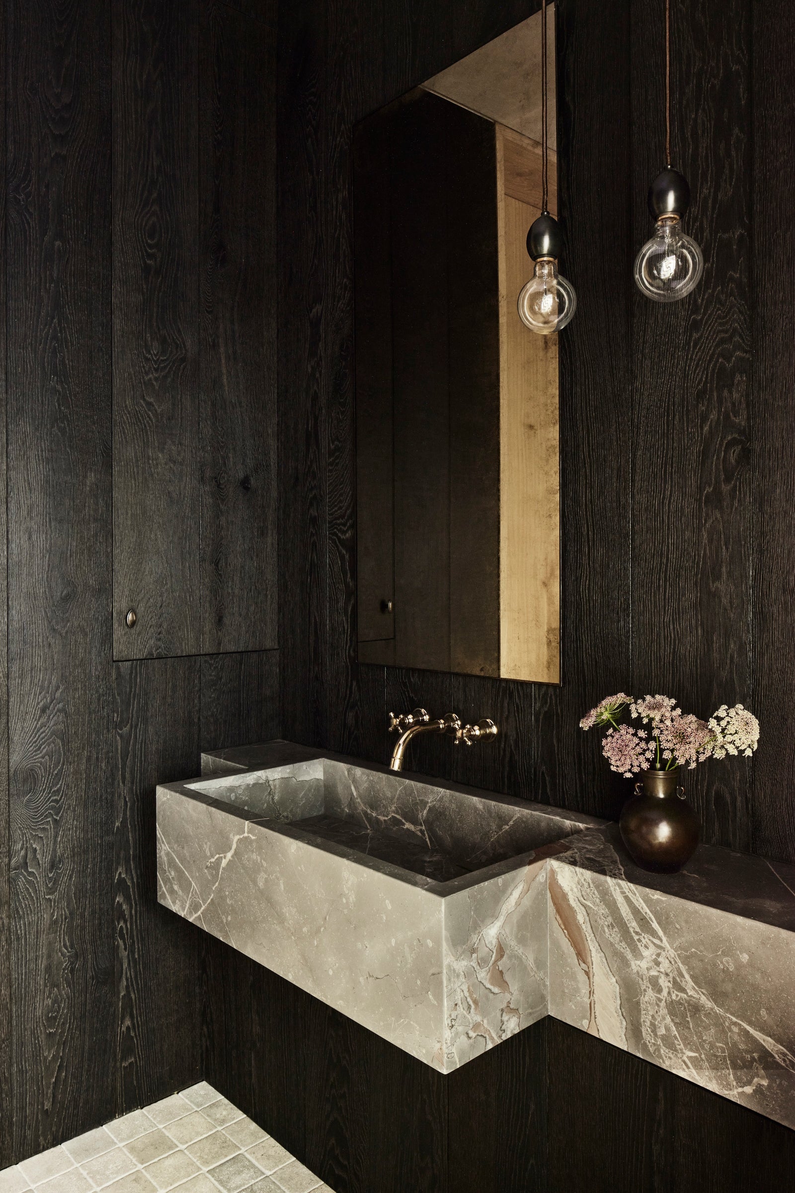 Heart oak paneling provides textural depth against a sculptural stone vanity, embodying the project's devotion to natural materiality.