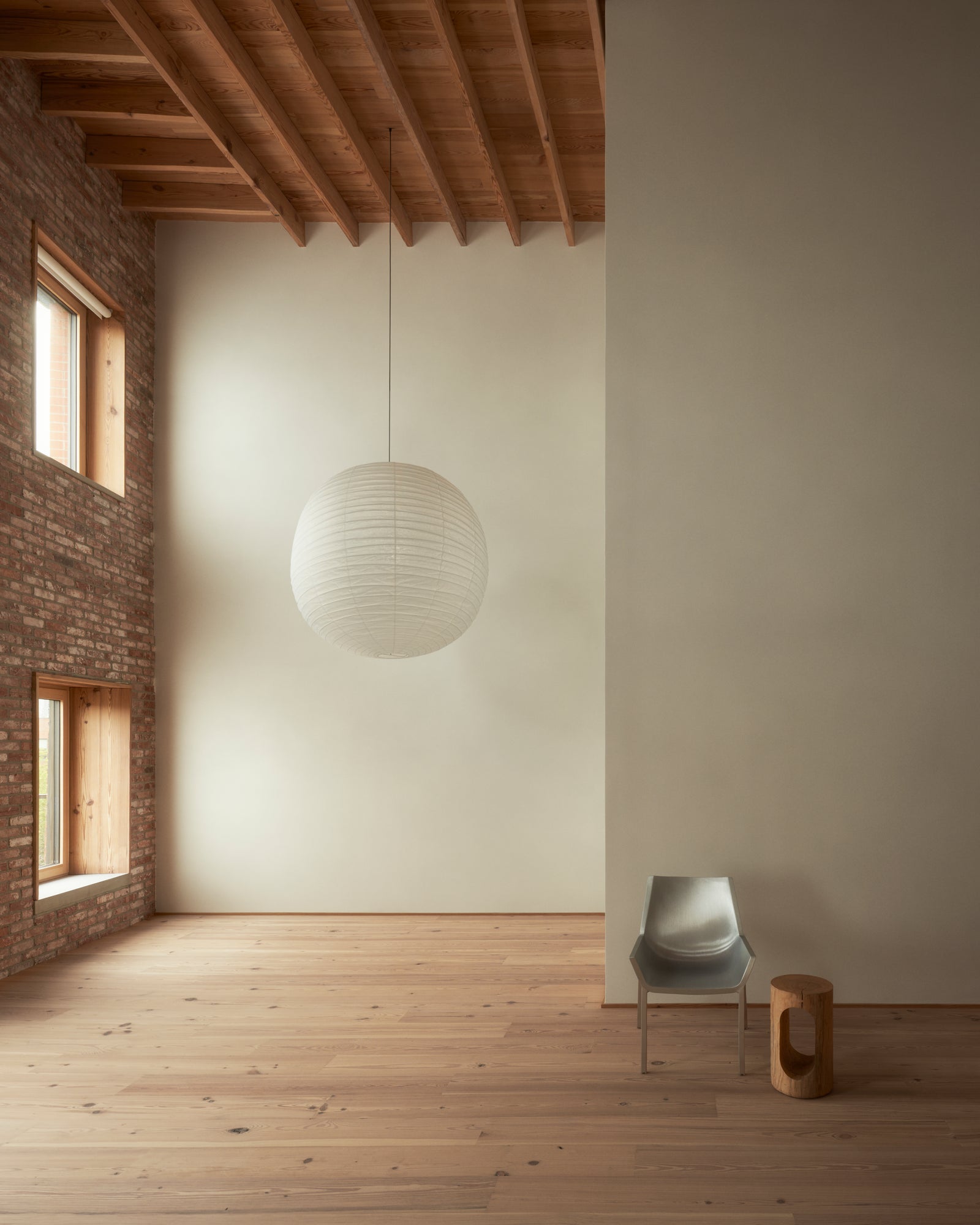 Double-height ceilings and exposed brick walls frame an expansive volume where wood surfaces bring warmth to dramatic industrial scale.
