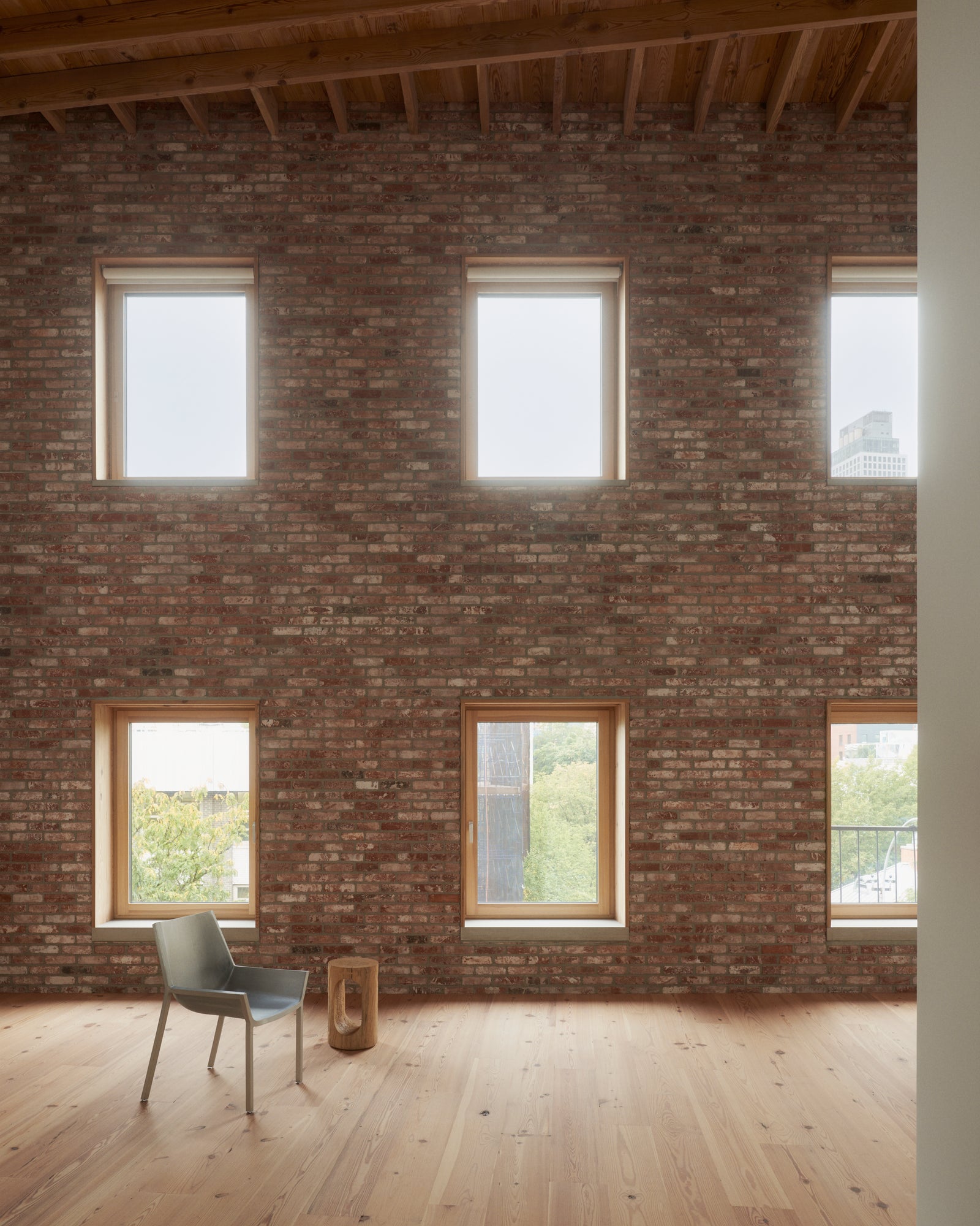 ix punched windows in weathered brick reveal the building's warehouse lineage, framed by exposed wood joists and filled with Brooklyn light.