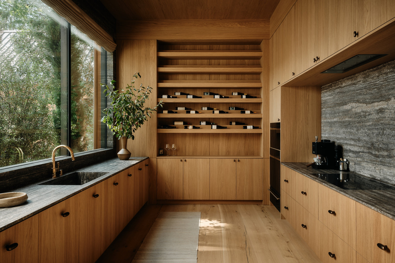 Custom oak cabinetry and wine rack display the warmth and precision of MADERA wood surfaces in this sophisticated kitchen design.