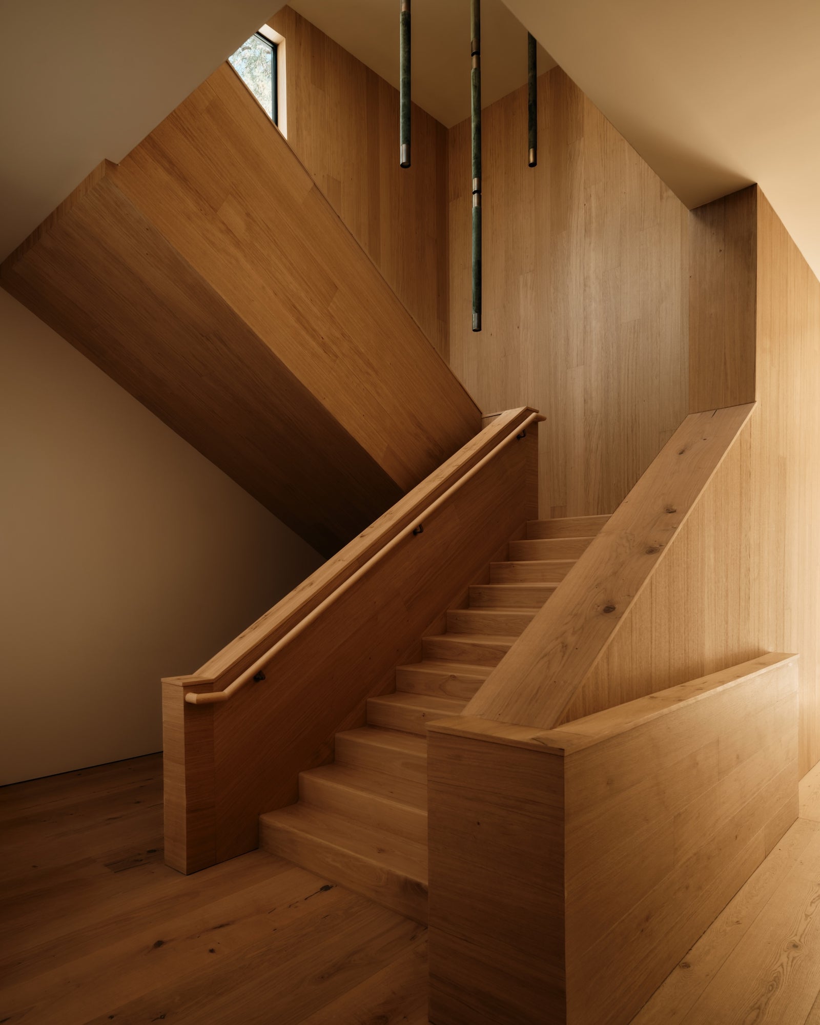 Sculptural oak staircase and wall cladding demonstrate the versatility of MADERA surfaces in modern residential design.