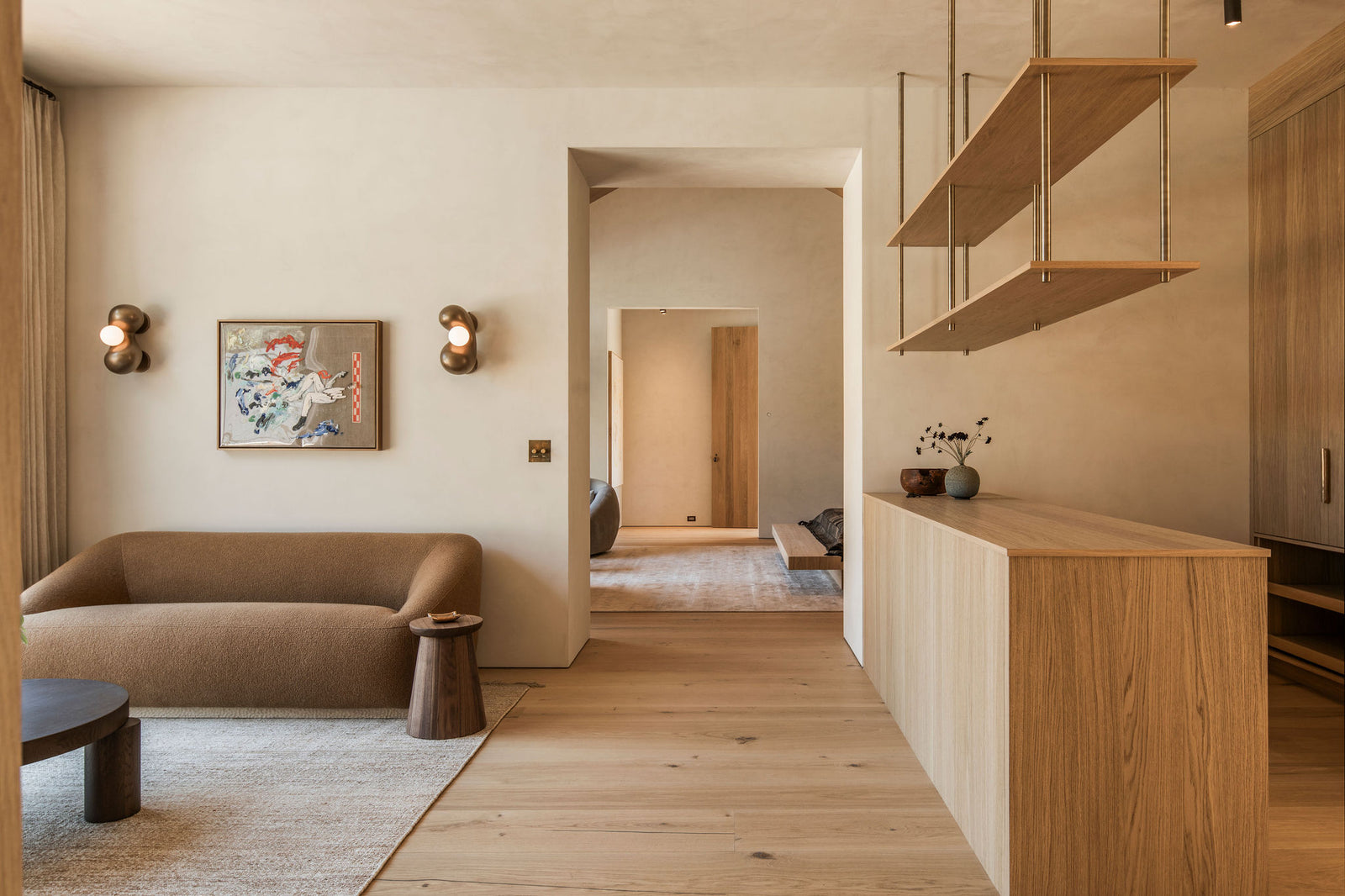 Wide-plank oak flooring flows throughout this open-plan living space, complemented by custom millwork and shelving systems.