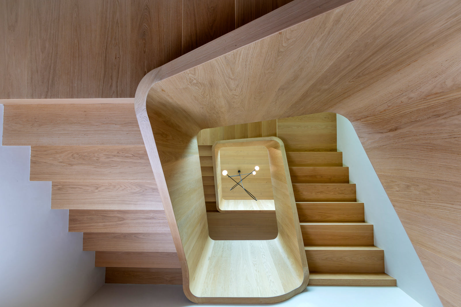 A sculptural staircase of smoked European oak showcases the beauty and versatility of continuous wood cladding.