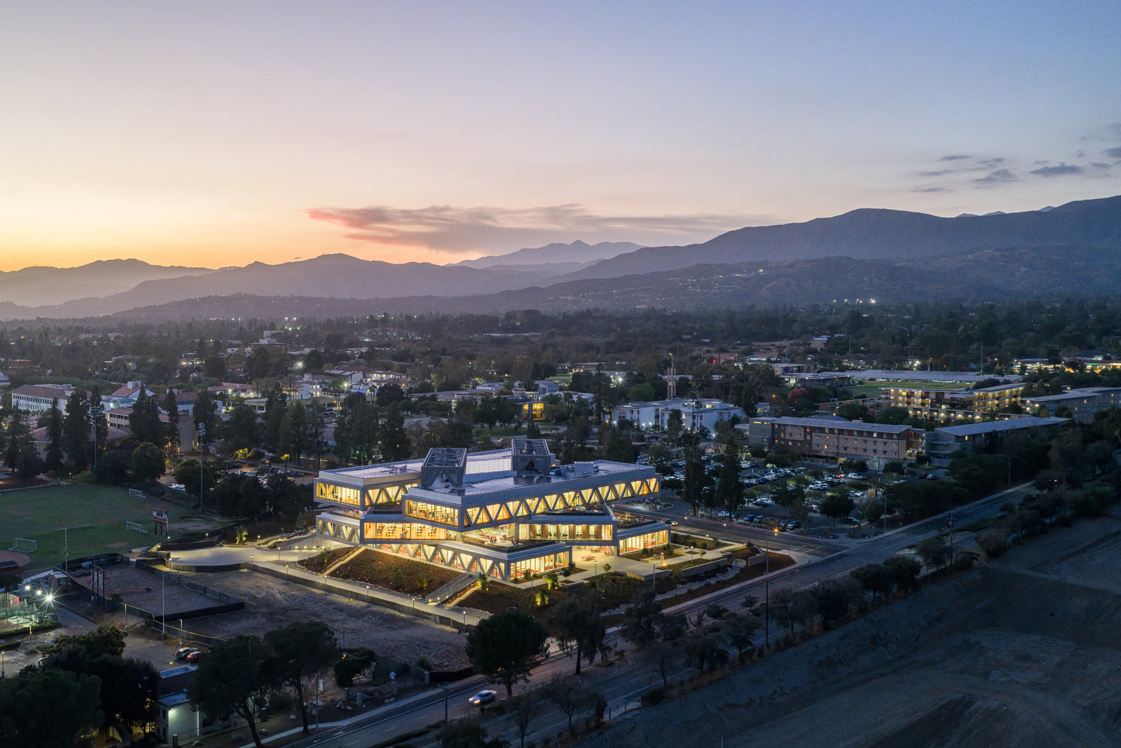 The Robert Day Sciences Center illuminated at dusk against the San Gabriel Mountains backdrop.